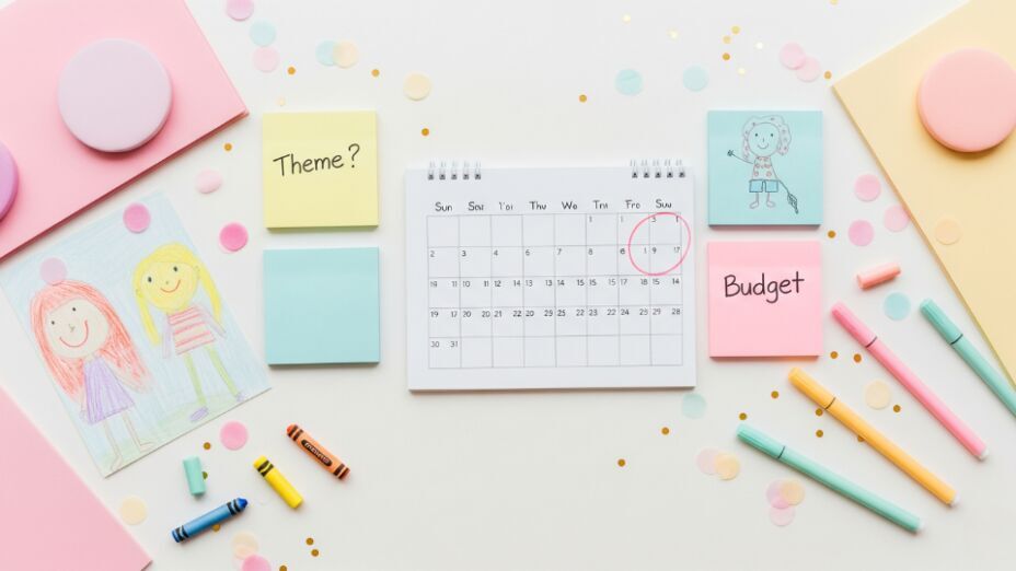 Flat-lay of calendar with circled party date, sticky notes for theme and budget, and child’s crayon drawing.