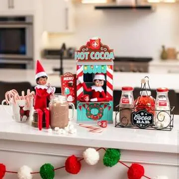 The Elf on the Shelf Insta-Props 2-in-1 Scene Kit with Reversible Pop Out Backdrop - Hot Cocoa Stand and Magic Shrinking Machine Scenes with Accessories